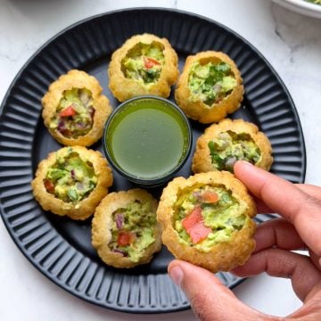 Mexican Golgappa filled with avocado stuffing and pani and avocado stuffing arranged on a plate and plain poori on the side.