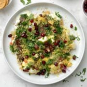 dahi papdi served in a white plate garnished with sev and papdi, dev and chutneys on the side