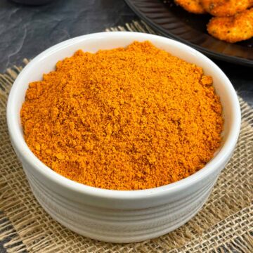 idli podi served in a bowl with ghee and podi idli on the side