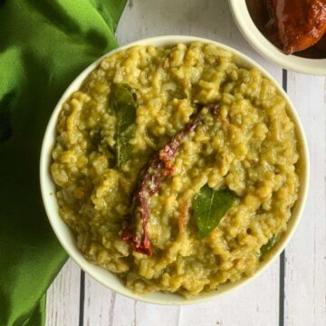 palak khichdi in a bowl with pickle on the side