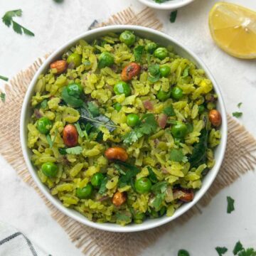 hariyali poha served in a bowl with coriander leaves and lemon wedge on the side
