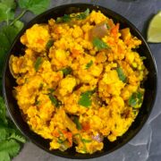 Dry Paneer Bhurji served in a black bowl with lemon wedge on side