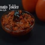 Tomato Thokku Andra Style served in a bowl with two raw tomato on the side