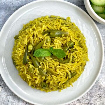 mint rice served on a plate garnished with mint leaves with a side of cucumber