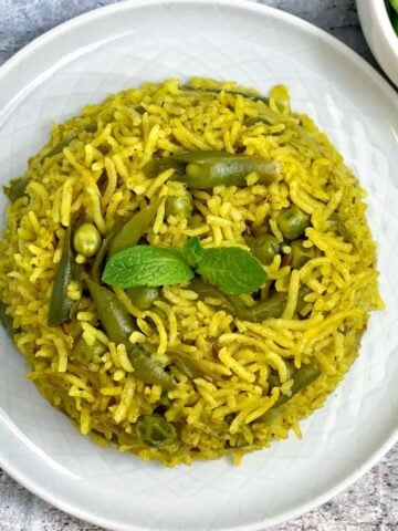 mint rice served on a plate garnished with mint leaves with a side of cucumber