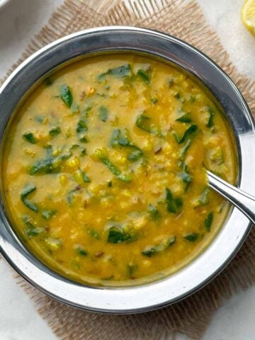 dal palak recipe served in a kadai with a spoon and rice on the side