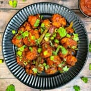 cauliflower manchurian served on a plate garnished with green onions and coriander leaves