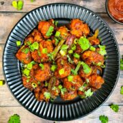 cauliflower manchurian served on a plate garnished with green onions and coriander leaves