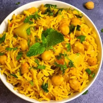 Chole Biryani served in a bowl with cooked chickpeas on side