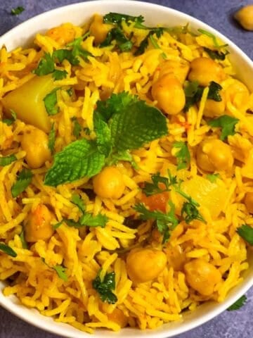 Chole Biryani (chickpea biryani) served in a bowl with cooked chickpeas on side