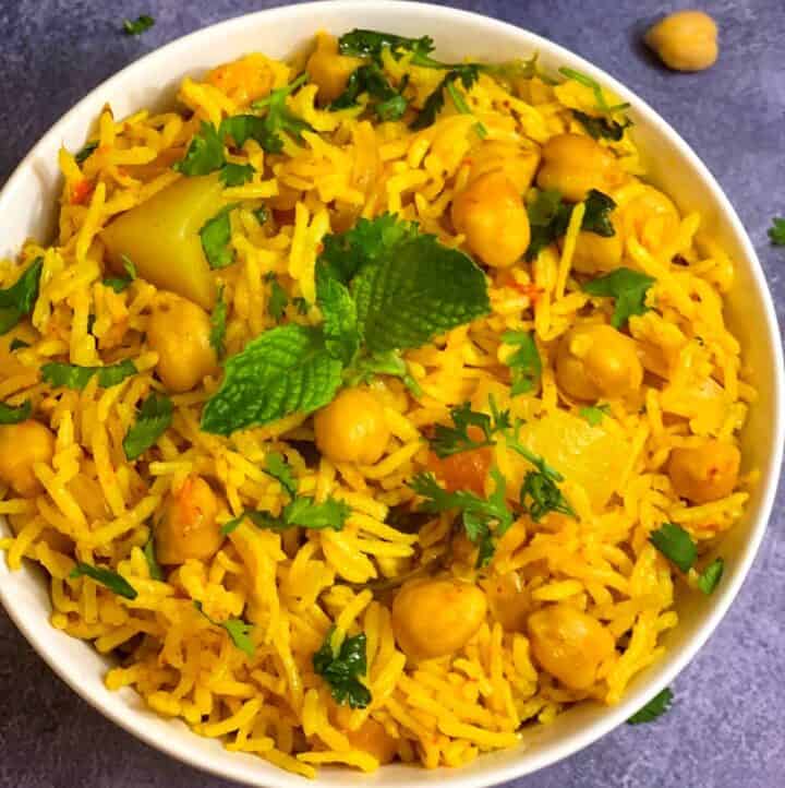 Chole Biryani (chickpea biryani) served in a bowl with cooked chickpeas on side