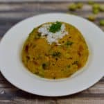 Avarekalu Upma served on a plate garnished with fresh coconut and cilantro