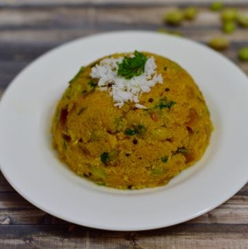 Avarekalu Upma served on a plate garnished with fresh coconut and cilantro