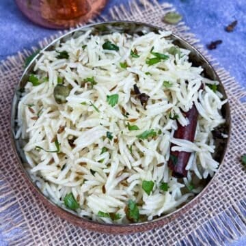 Restaurant style Instant Pot Jeera/cumin rice served in a bowl with cilantro on the side