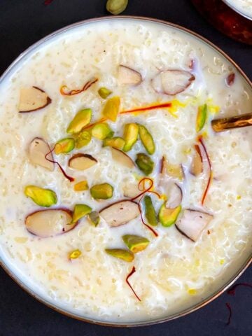 rice kheer/pudding served in a copper bowl with cardamom pods on side