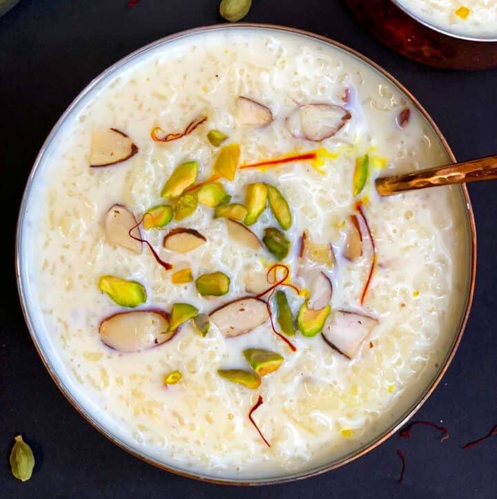 rice kheer/pudding served in a copper bowl with cardamom pods on side