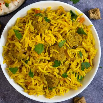 Soya Chunks Biryani served in a bowl garnished with cilantro and raita on the side