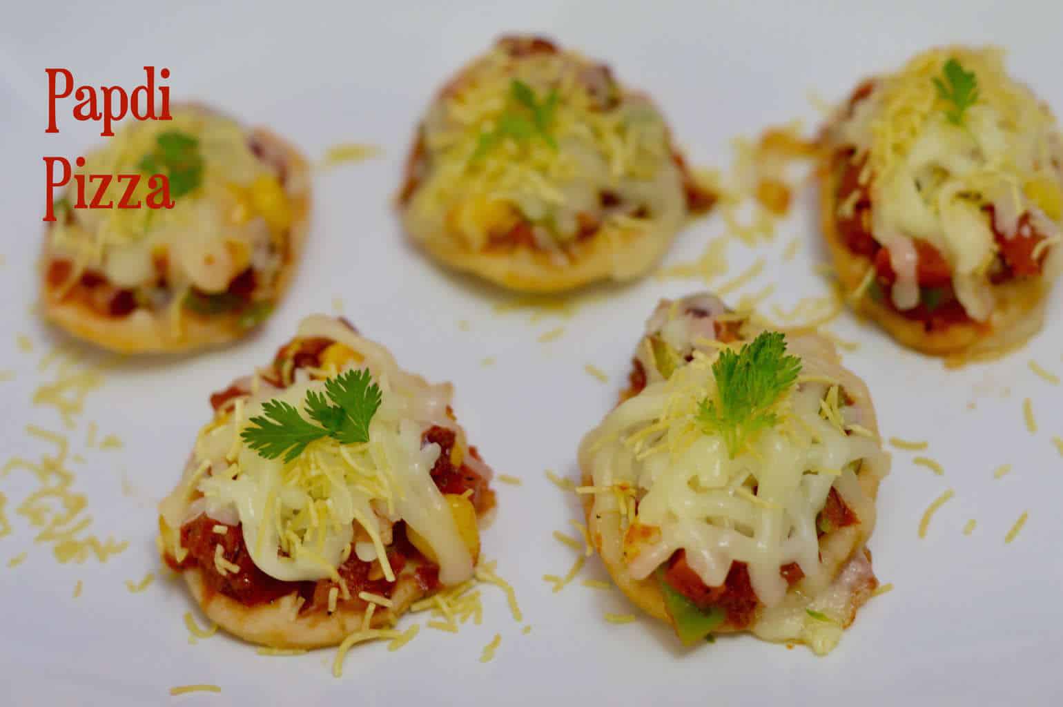 Papdi Pizza|Tea Time Snack is a simple, easy snack recipe where papris are spread with pizza sauce mixed with some toppings and and then topped with shredded cheese and baked.