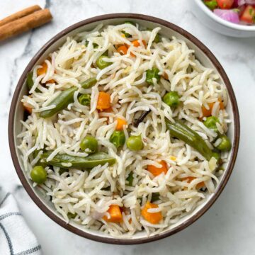 instant pot coconut milk pulao served in a bowl with spices and salad on the side