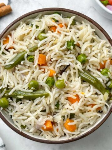 instant pot coconut milk pulao served in a bowl with spices and salad on the side