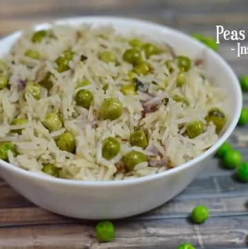 Instant Pot Peas Pulao served in a white bowl with few green peas fallen on the sheet