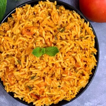 tomato pulao served in a black bowl garnished with mint leaves