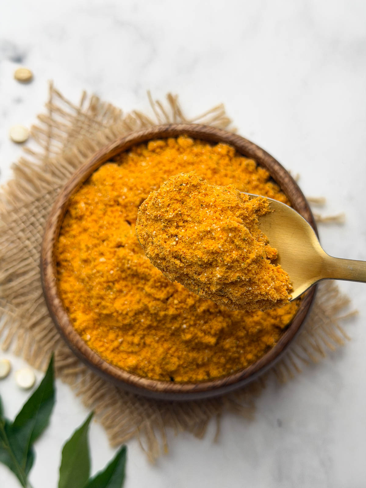 Roasted Chana Dal Chutney Powder (Hurigadale Chutney Pudi) in a wooden bowl with a spoonful held in hand.