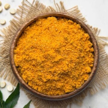 Hurigadale chutney pudi served in a wooden serving bowl with curry leaves kept for decoration.