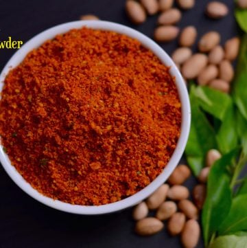 Peanut Chutney Powder (shenga chutney pudi) served in a white bowl with raw peanuts and curry leaves on the side