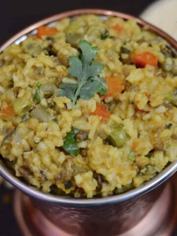 Vegetable Khichdi served in a copper vessel with kadhi on the side