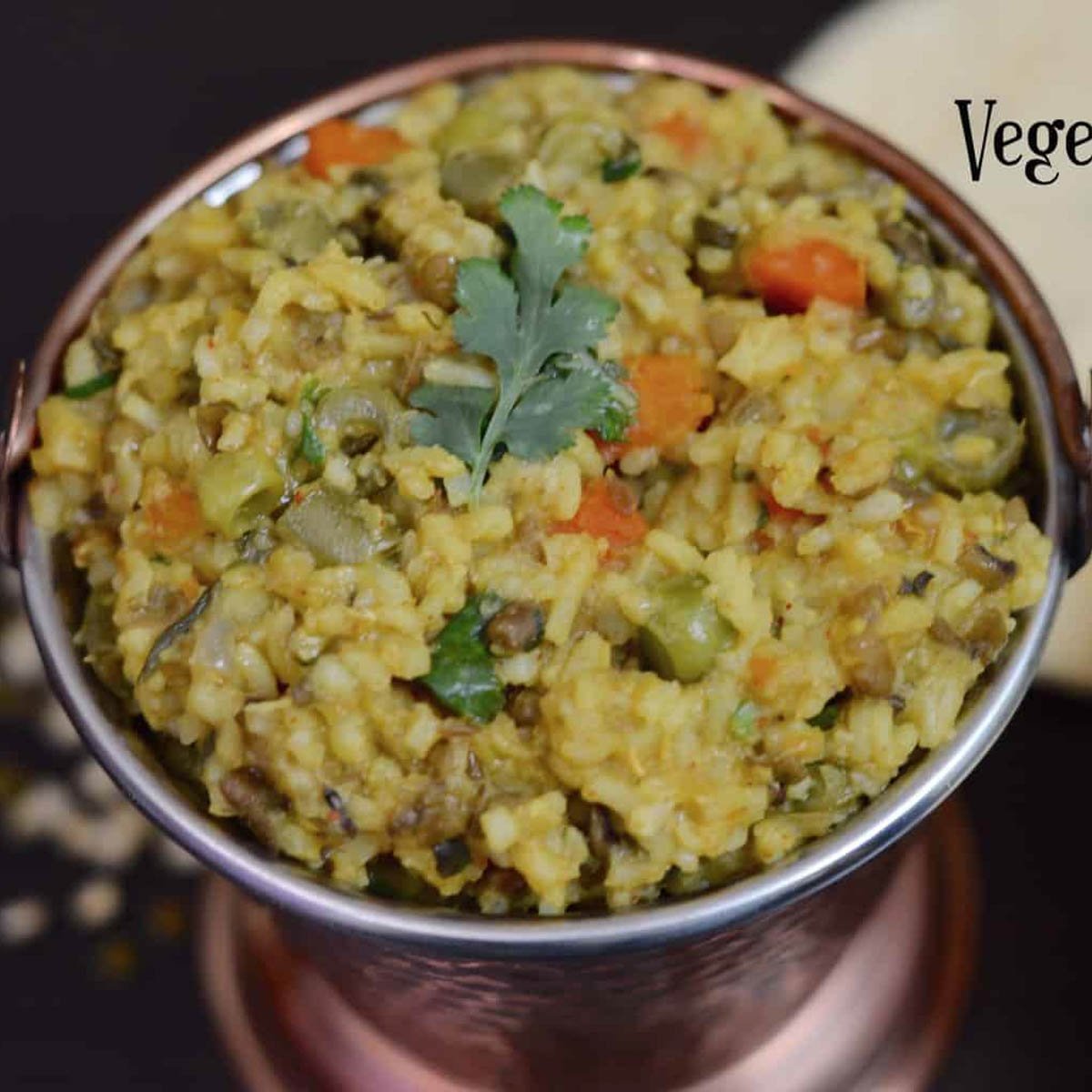 Vegetable Khichdi served in a copper vessel with kadhi on the side