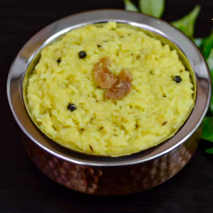 Ven Pongal or Khara Pongal served in a copper bottom serving bowl with curry leaves on side