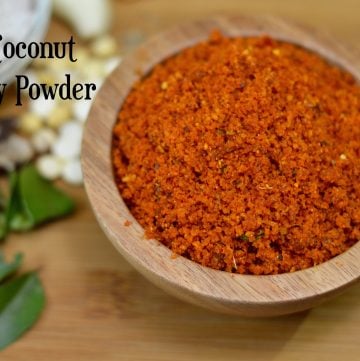 dry coconut chutney powder served in a wooden bowl with curry leaves on the side