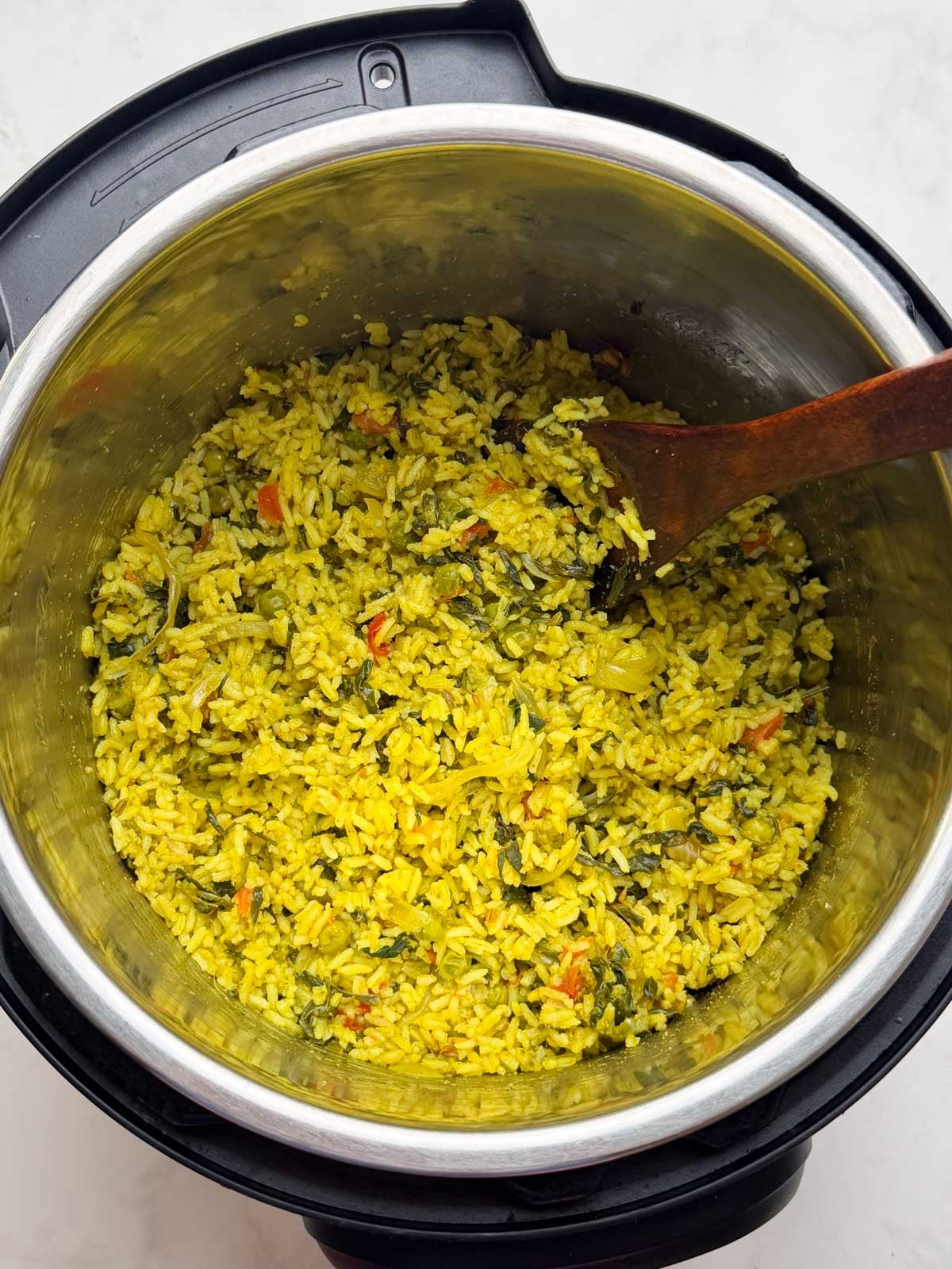 Menthya bhat in instant pot insert with a wooden spoon.