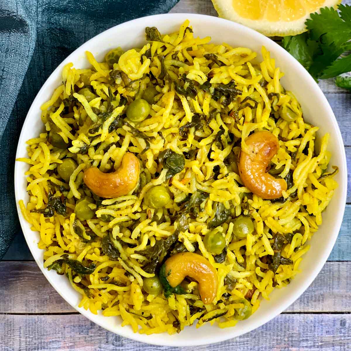 Spinach Rice served in a bowl with lemon wedge and cilantro on side