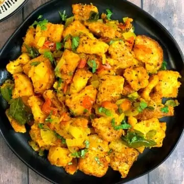 bread upma served on a black plate garnished with coriander leaves