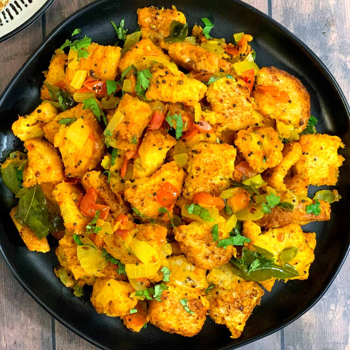 bread upma served on a black plate garnished with coriander leaves