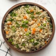 Little millet upma served in a wooden bowl with peanut chutney powder on the side.
