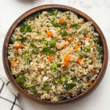 Little millet upma served in a wooden bowl with peanut chutney powder on the side.