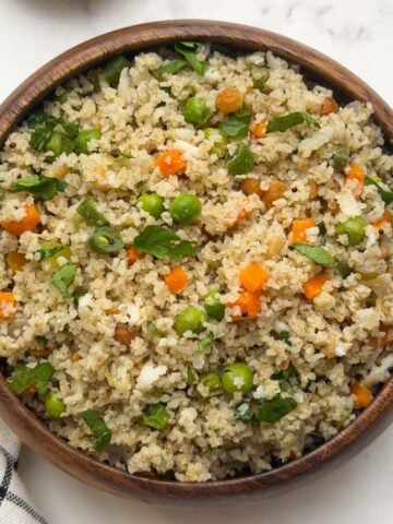 Little millet upma served in a wooden bowl with peanut chutney powder on the side.