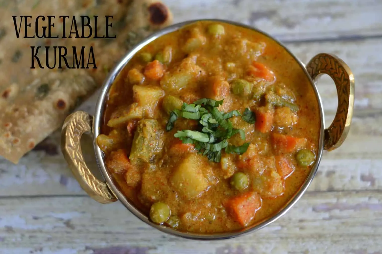 Vegetable Kurma served in a kadai garnished with cilantro with paratha on the side