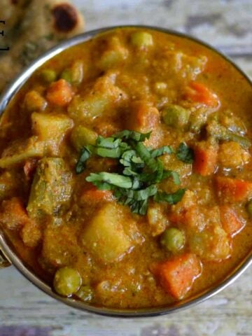 Vegetable Kurma served in a kadai with paratha on the side