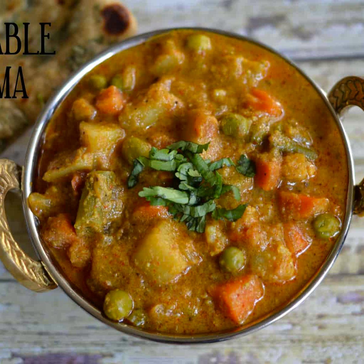 Vegetable Kurma served in a kadai with paratha on the side