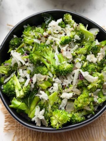 broccoli poriyal served in a black bowl with steamed rice and tomato rasam on the side.