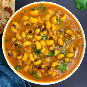 black eye e pea curry served in a white bow; with indian flatbread on the side