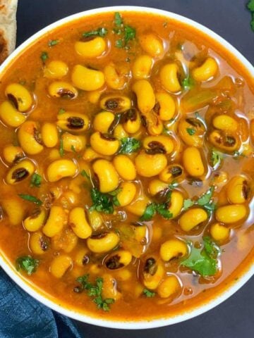 instant pot black eyed peas curry served in a white bowl with indian flatbread on the side