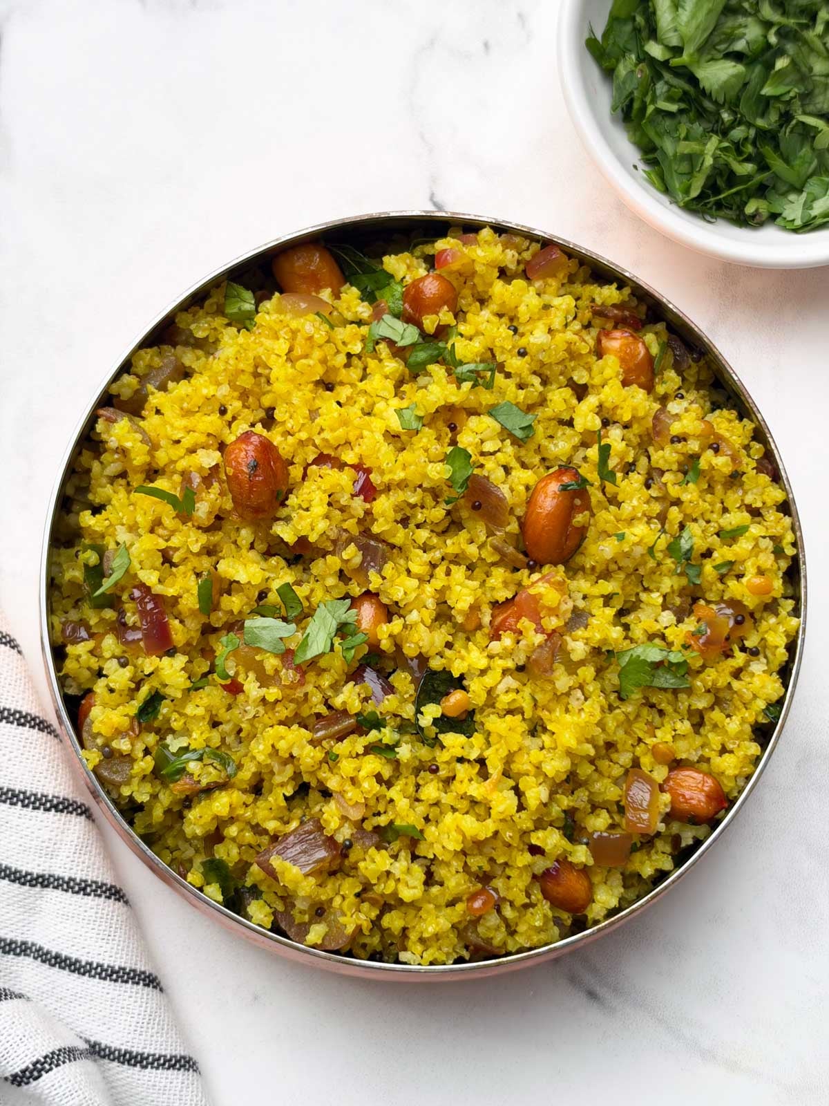 little millet lemon rice served in a copper color bowl and coriander on the side.