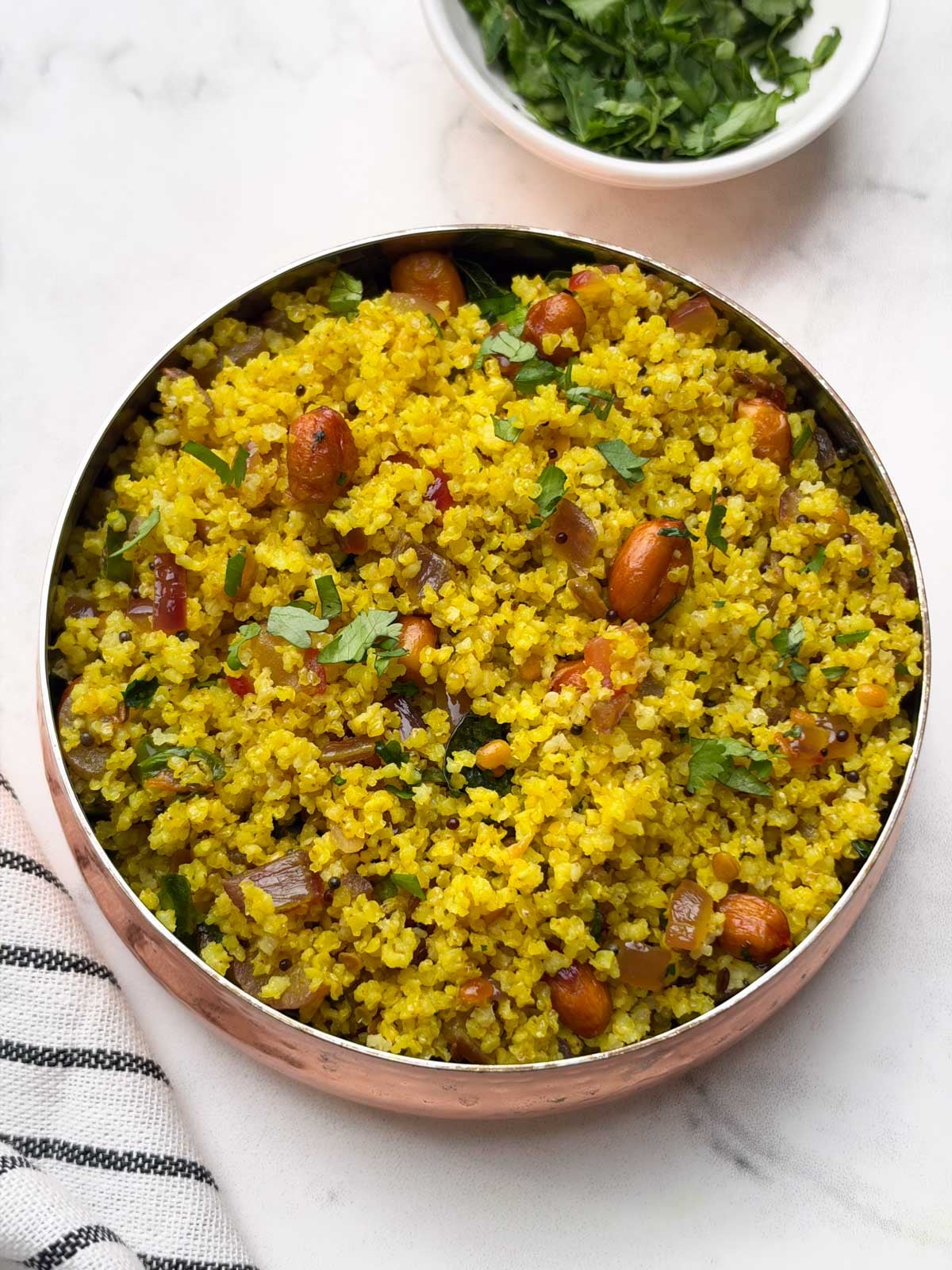 little millet lemon rice served in a copper color bowl and coriander on the side.
