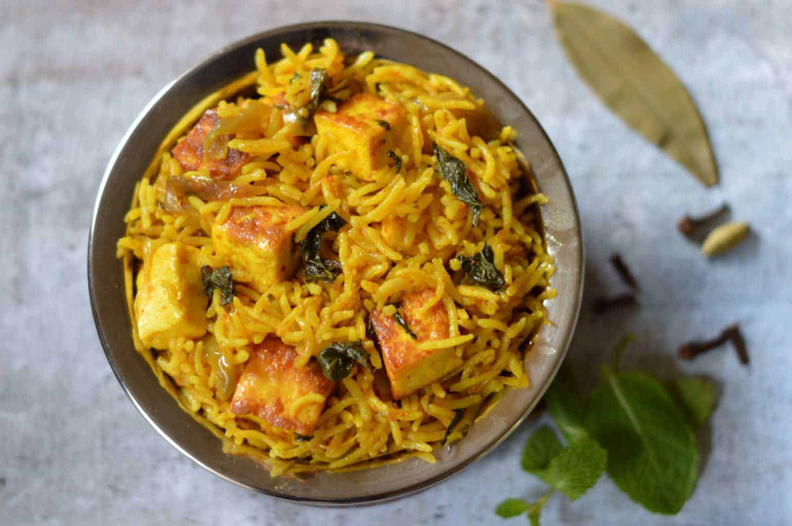 Paneer Biryani served in a bowl with spices on the side