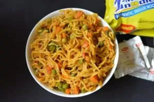 Vegetable Masala Maggi served in a bowl with maggi noodles packet on the side with maggi taste makers
